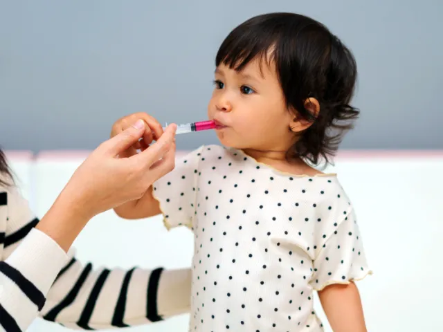 young child taking correct dosage of medicine